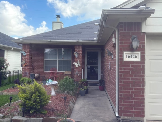16426 Eton Brook Ln, Houston, TX 77073 - view of exterior entry with brick siding, a chimney, and a shingled roof