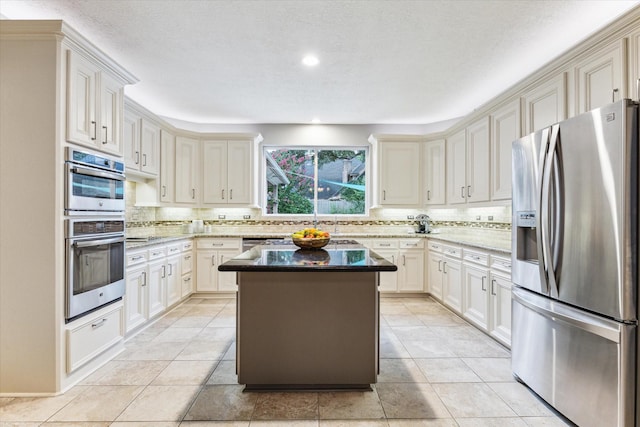 6019 Oak Creek Ln, Spring, TX 77379 - kitchen featuring stainless steel appliances, backsplash, light stone counters, a center island, and recessed lighting