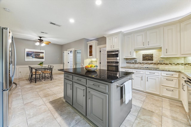 6019 Oak Creek Ln, Spring, TX 77379 - kitchen featuring appliances with stainless steel finishes, gray cabinets, a ceiling fan, tasteful backsplash, and dark stone counters