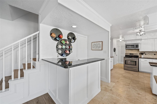 19702 Sweet Forest Ln, Humble, TX 77346 - kitchen featuring stainless steel appliances, a textured ceiling, white cabinetry, backsplash, and a peninsula