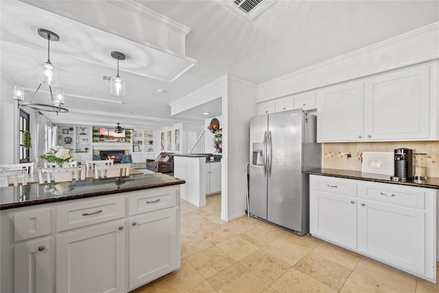 19702 Sweet Forest Ln, Humble, TX 77346 - kitchen featuring stainless steel fridge with ice dispenser, white cabinets, decorative backsplash, a warm lit fireplace, and crown molding