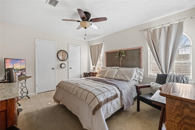 19702 Sweet Forest Ln, Humble, TX 77346 - bedroom featuring light colored carpet, a textured ceiling, ceiling fan, and multiple closets