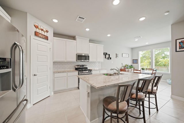2849 Terrace Grove Dr, Conroe, TX 77304 - kitchen featuring stainless steel appliances, backsplash, light tile patterned floors, a center island with sink, and recessed lighting