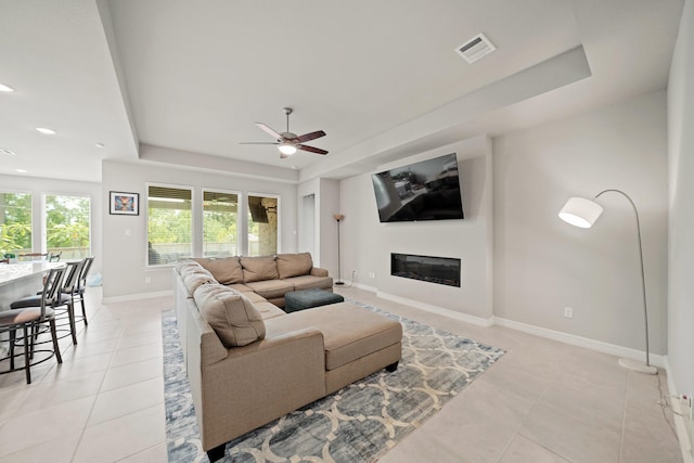 2849 Terrace Grove Dr, Conroe, TX 77304 - living area featuring a tray ceiling, light tile patterned floors, ceiling fan, a glass covered fireplace, and recessed lighting
