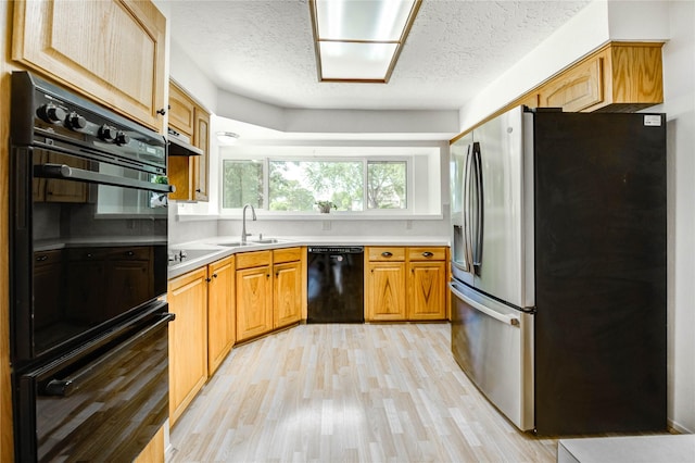 12327 Meadowhollow Dr, Meadows Place, TX 77477 - kitchen with black appliances, light wood-style flooring, a textured ceiling, light countertops, and under cabinet range hood