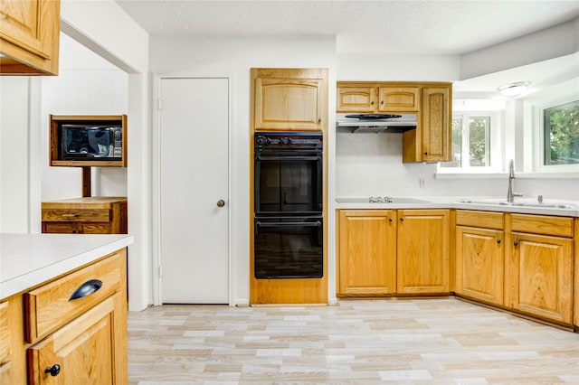 12327 Meadowhollow Dr, Meadows Place, TX 77477 - kitchen featuring black appliances, light wood-type flooring, light countertops, under cabinet range hood, and a textured ceiling