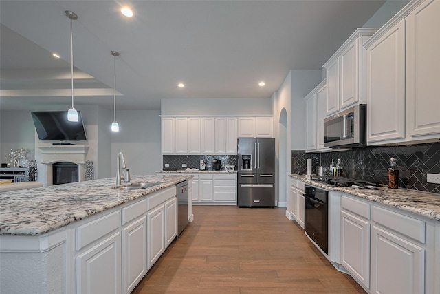 7707 Leighton Trl, Pasadena, TX 77505 - kitchen with appliances with stainless steel finishes, wood finished floors, white cabinetry, a fireplace, and backsplash
