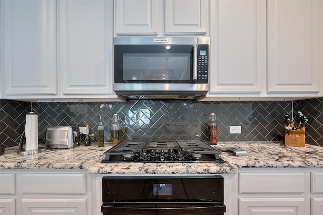 7707 Leighton Trl, Pasadena, TX 77505 - kitchen featuring stainless steel microwave, black gas stovetop, white cabinetry, oven, and tasteful backsplash