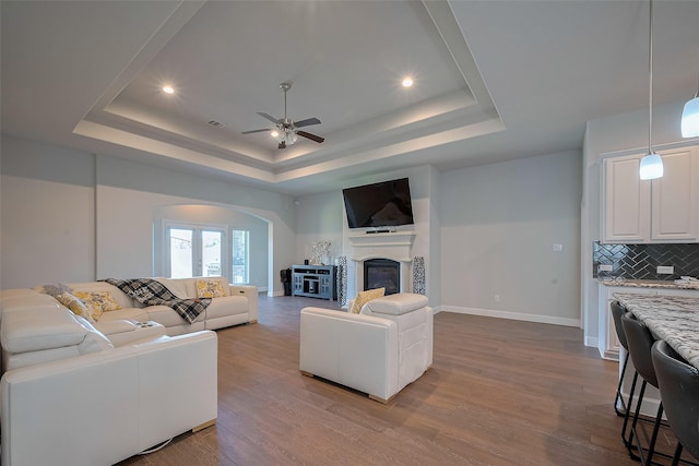 7707 Leighton Trl, Pasadena, TX 77505 - living area with a tray ceiling, arched walkways, dark wood finished floors, ceiling fan, and recessed lighting