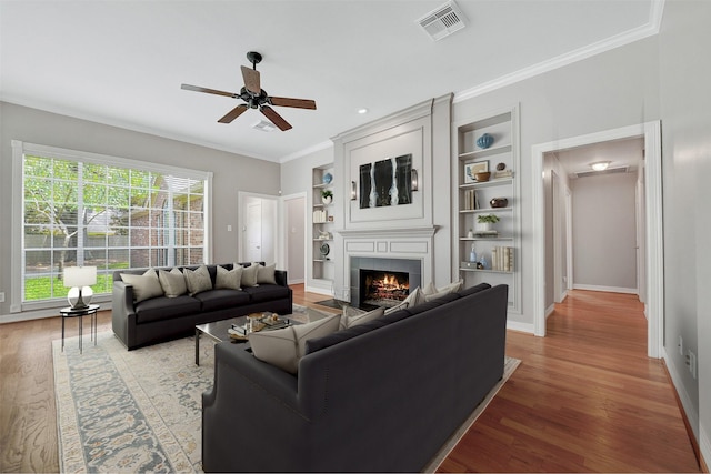 3519 E Pine Brook Way, Houston, TX 77059 - living area featuring a tiled fireplace, a ceiling fan, wood finished floors, built in features, and ornamental molding