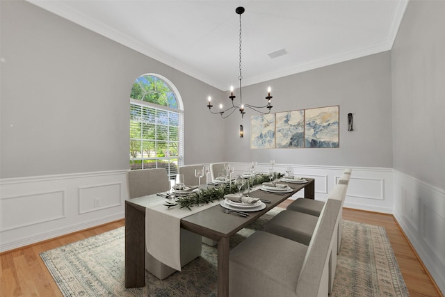 3519 E Pine Brook Way, Houston, TX 77059 - dining space with a chandelier, a wainscoted wall, wood finished floors, crown molding, and a decorative wall