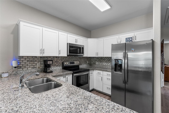 16887 Balmoral St, Montgomery, TX 77316 - kitchen featuring stainless steel appliances, light stone counters, white cabinetry, backsplash, and dark wood-style floors