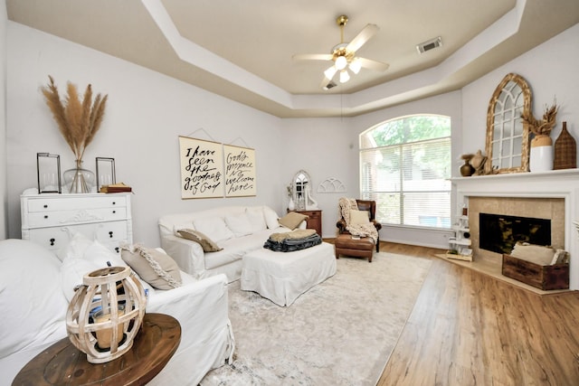 70 N Lace Arbor Dr, The Woodlands, TX 77382 - living area featuring a tray ceiling, a ceiling fan, wood finished floors, and a tiled fireplace