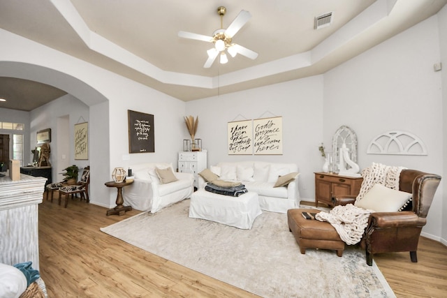 70 N Lace Arbor Dr, The Woodlands, TX 77382 - living room with arched walkways, a raised ceiling, ceiling fan, and light wood-type flooring