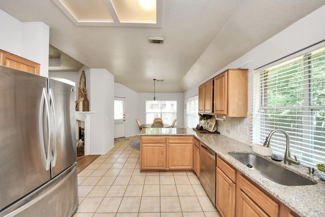 70 N Lace Arbor Dr, The Woodlands, TX 77382 - kitchen featuring appliances with stainless steel finishes, a peninsula, vaulted ceiling, light tile patterned flooring, and light stone counters