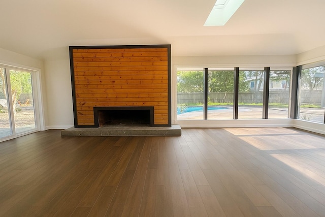 7810 Nairn St, Houston, TX 77074 - unfurnished living room featuring a skylight, a large fireplace, healthy amount of natural light, and dark wood-style flooring