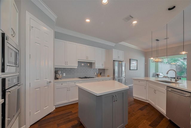 4006 Lanark Ln, Houston, TX 77025 - kitchen featuring appliances with stainless steel finishes, a kitchen island, light countertops, dark wood-style flooring, and hanging light fixtures