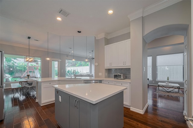 4006 Lanark Ln, Houston, TX 77025 - kitchen featuring a peninsula, light countertops, dark wood-style floors, a center island, and arched walkways