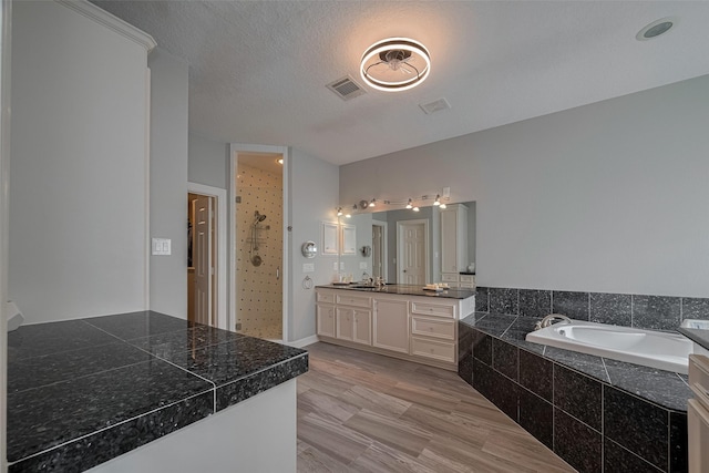 4006 Lanark Ln, Houston, TX 77025 - full bathroom featuring vanity, a garden tub, a tile shower, and a textured ceiling