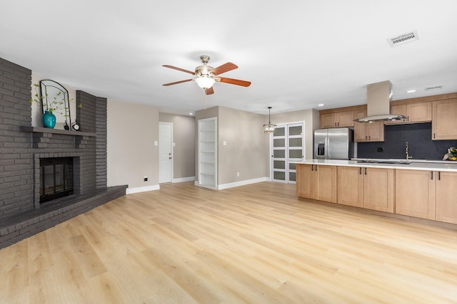 2807 Canary Ln, Humble, TX 77396 - kitchen with island range hood, stainless steel fridge with ice dispenser, a ceiling fan, a brick fireplace, and light wood-type flooring