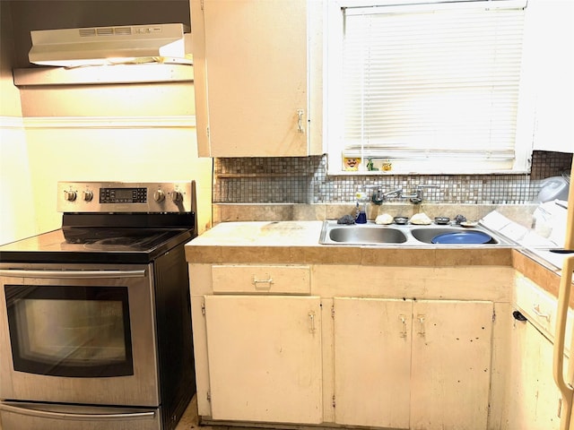 5305 Rapido Rd, Houston, TX 77033 - kitchen featuring stainless steel electric stove, under cabinet range hood, light countertops, and backsplash