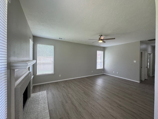4607 Blue Rose Cir, Missouri City, TX 77459 - unfurnished living room featuring a textured ceiling, dark wood finished floors, ceiling fan, and a brick fireplace
