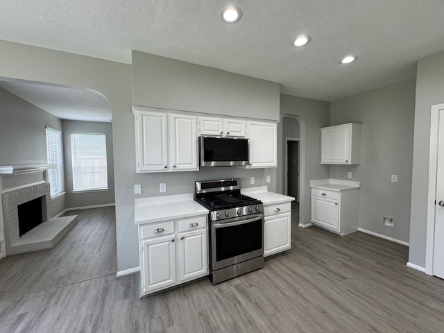 4607 Blue Rose Cir, Missouri City, TX 77459 - kitchen featuring appliances with stainless steel finishes, arched walkways, light wood-style floors, light countertops, and a textured ceiling
