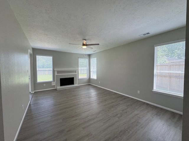 4607 Blue Rose Cir, Missouri City, TX 77459 - unfurnished living room featuring a textured ceiling, a ceiling fan, dark wood-type flooring, and a fireplace with raised hearth
