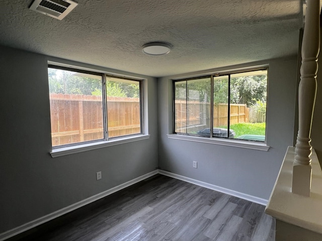 7726 Ashmole Ln, Houston, TX 77088 - empty room with dark wood-style floors, plenty of natural light, and a textured ceiling