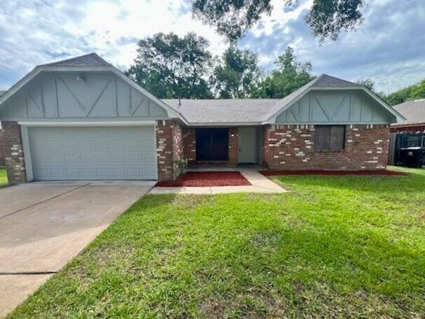 7726 Ashmole Ln, Houston, TX 77088 - english style home with a garage, concrete driveway, brick siding, and a front lawn