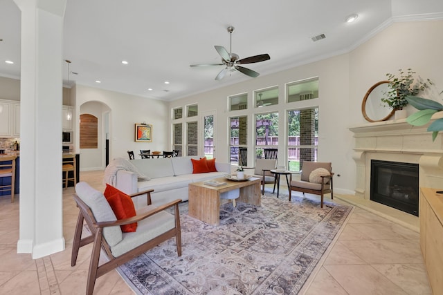 18774 Monetta Dr, New Caney, TX 77357 - living area with crown molding, arched walkways, a glass covered fireplace, ceiling fan, and recessed lighting