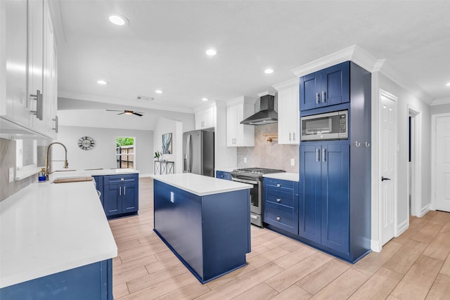 2504 Leroy St, Pearland, TX 77581 - kitchen with appliances with stainless steel finishes, wall chimney range hood, blue cabinetry, light countertops, and ornamental molding