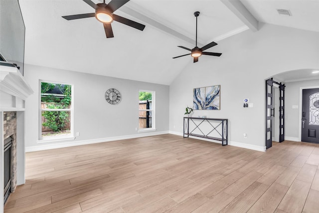2504 Leroy St, Pearland, TX 77581 - unfurnished living room with a ceiling fan, arched walkways, beamed ceiling, a fireplace, and light wood-style flooring