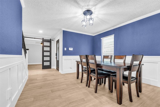 2504 Leroy St, Pearland, TX 77581 - dining room with a barn door, a textured ceiling, a wainscoted wall, ornamental molding, and a decorative wall