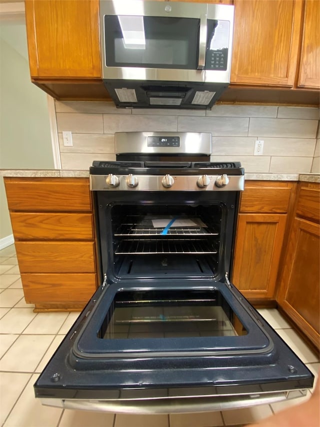 2512 Pine St, Galveston, TX 77551 - kitchen with appliances with stainless steel finishes, light countertops, brown cabinets, and light tile patterned floors