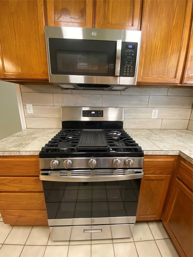 2512 Pine St, Galveston, TX 77551 - kitchen featuring appliances with stainless steel finishes, light countertops, backsplash, and brown cabinets