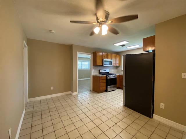 2512 Pine St, Galveston, TX 77551 - kitchen featuring appliances with stainless steel finishes, light countertops, a ceiling fan, light tile patterned floors, and brown cabinets