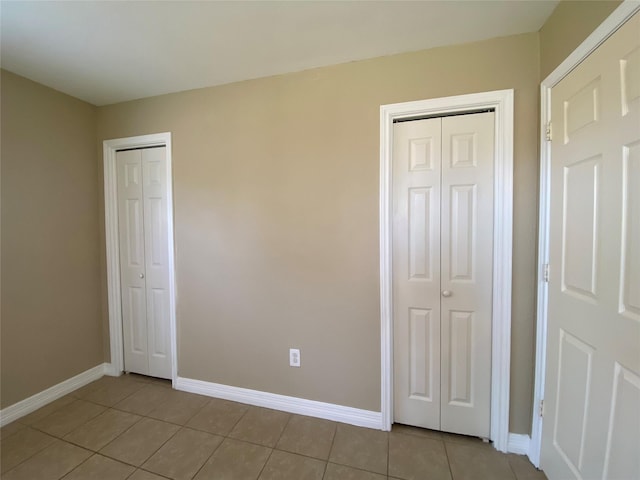 2512 Pine St, Galveston, TX 77551 - unfurnished bedroom with light tile patterned flooring and two closets