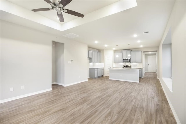 828 Laguna Green Ln, Katy, TX 77493 - unfurnished living room featuring a ceiling fan, light wood-style floors, recessed lighting, and a tray ceiling