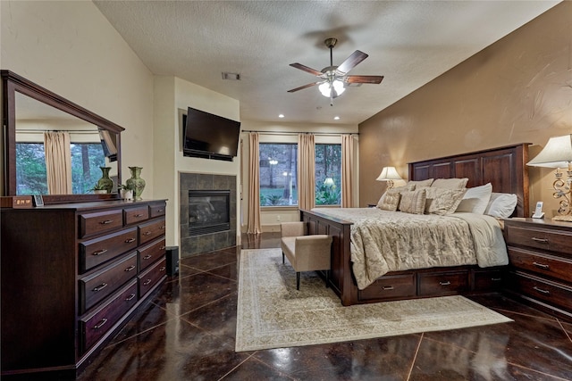 3 Creekwood Dr, Montgomery, TX 77356 - bedroom featuring a tiled fireplace, multiple windows, a textured ceiling, and a ceiling fan