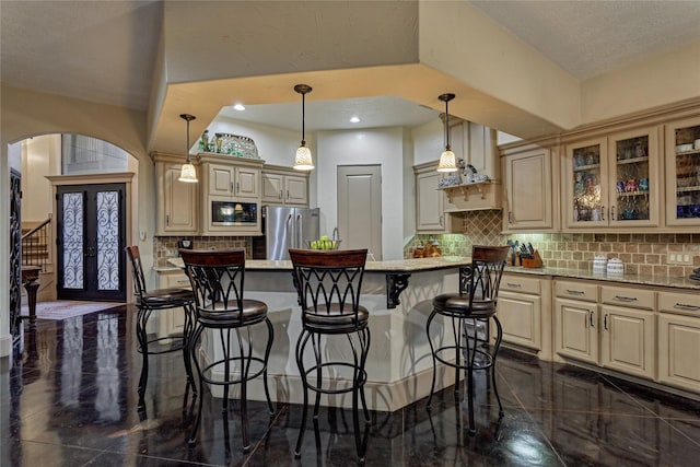 3 Creekwood Dr, Montgomery, TX 77356 - kitchen with built in microwave, freestanding refrigerator, arched walkways, a kitchen bar, and cream cabinets
