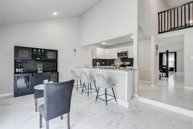 12102 Benmore Dr, Houston, TX 77099 - kitchen with stainless steel appliances, light marble finish floors, white cabinets, light stone counters, and a breakfast bar area