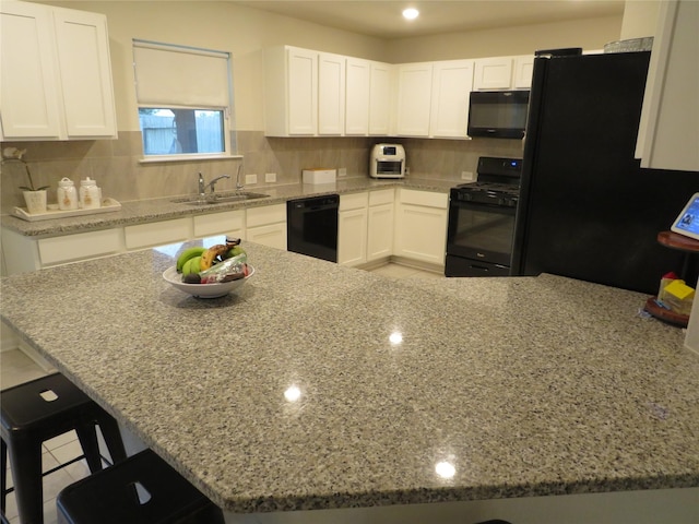 5218 Stone Castle Tower St, Katy, TX 77493 - kitchen with black appliances, white cabinets, light stone countertops, and a kitchen breakfast bar