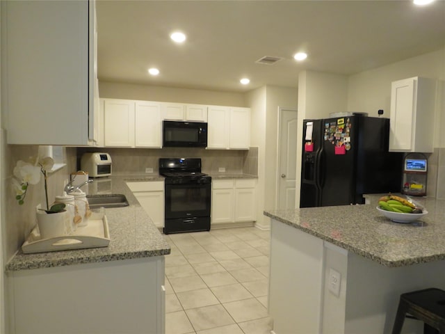 5218 Stone Castle Tower St, Katy, TX 77493 - kitchen featuring black appliances, white cabinetry, decorative backsplash, light stone counters, and a breakfast bar area