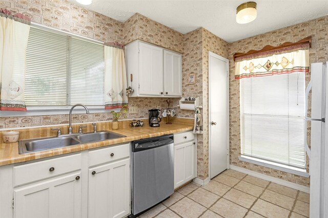 4818 Lost Lake Ln, Spring, TX 77388 - kitchen with stainless steel dishwasher, white cabinetry, wallpapered walls, light countertops, and light tile patterned floors