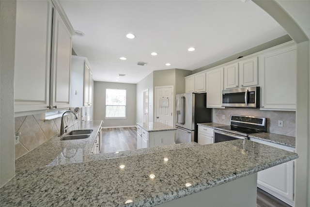21326 Pebble Pine Trl, Cypress, TX 77433 - kitchen featuring appliances with stainless steel finishes, light stone counters, a center island, recessed lighting, and white cabinets