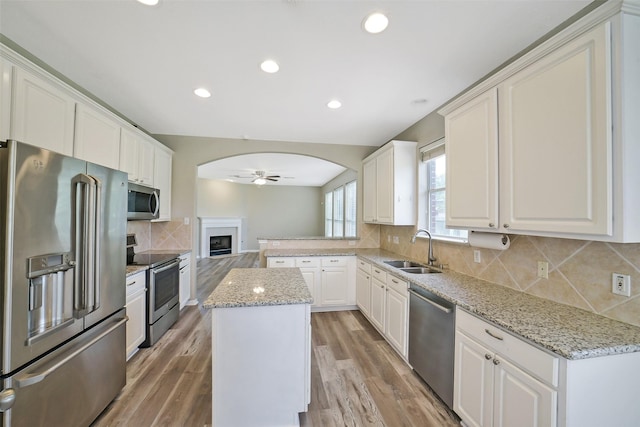 21326 Pebble Pine Trl, Cypress, TX 77433 - kitchen with appliances with stainless steel finishes, ceiling fan, decorative backsplash, light stone counters, and a fireplace