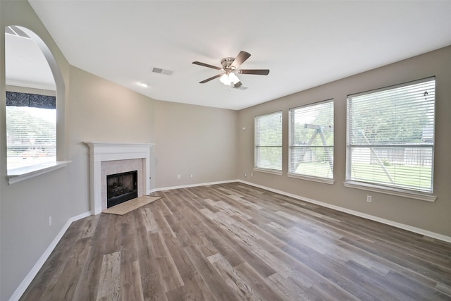 21326 Pebble Pine Trl, Cypress, TX 77433 - unfurnished living room featuring a ceiling fan, wood finished floors, a fireplace, and arched walkways