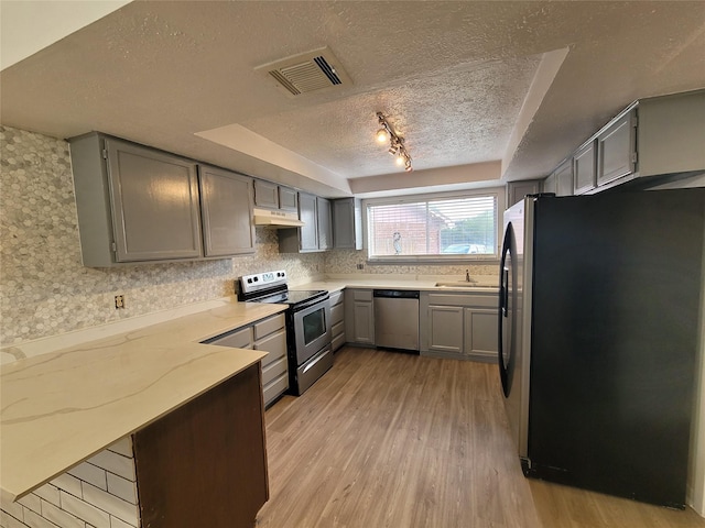13930 New Village Ln, Sugar Land, TX 77498 - kitchen featuring stainless steel appliances, gray cabinetry, a textured ceiling, light wood-style flooring, and under cabinet range hood