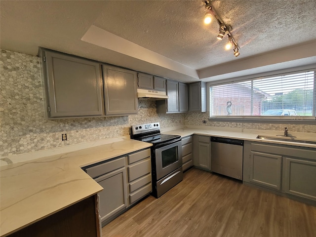 13930 New Village Ln, Sugar Land, TX 77498 - kitchen featuring stainless steel appliances, gray cabinets, a textured ceiling, light wood-style flooring, and under cabinet range hood